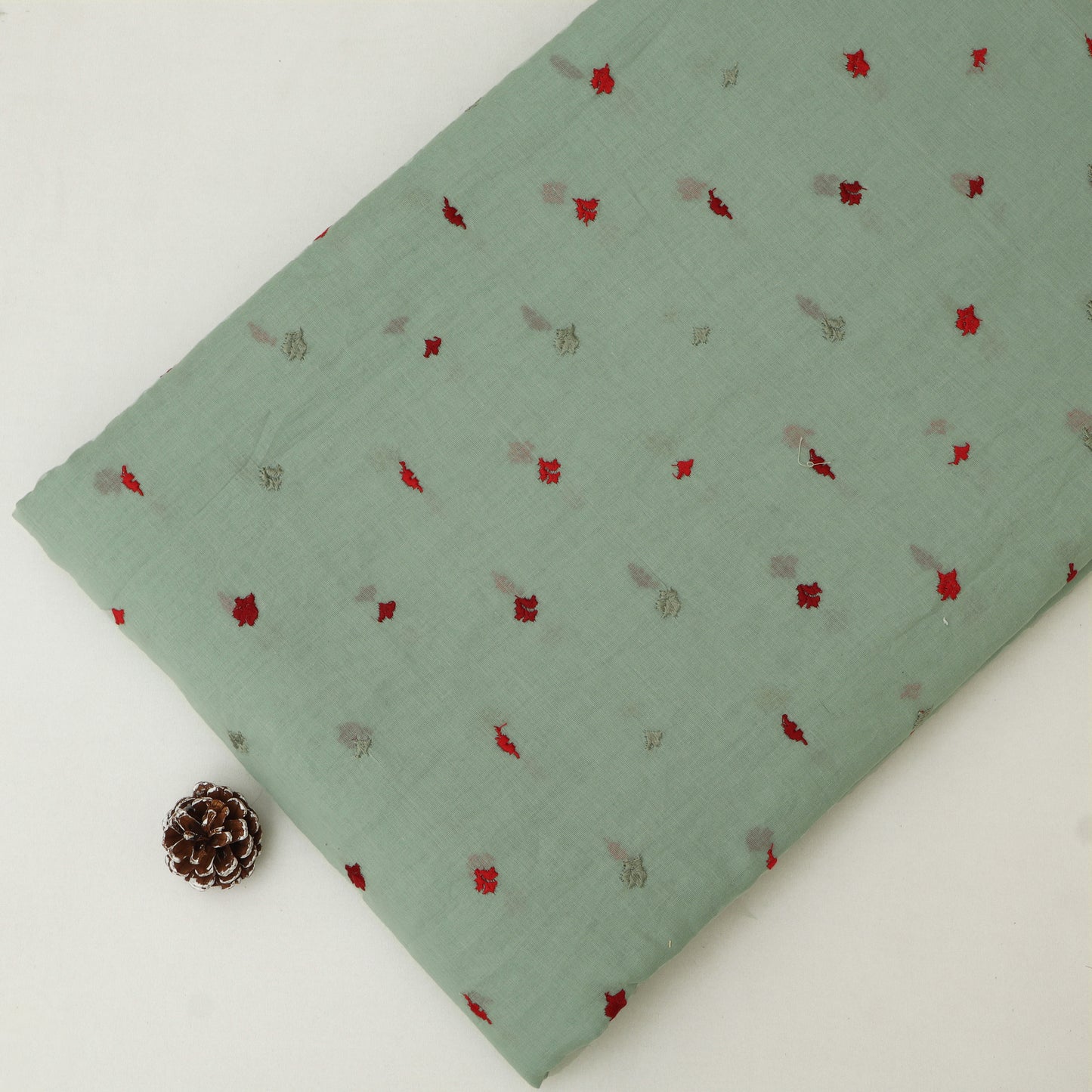 Green fabric with small red and gray patterns on a white background