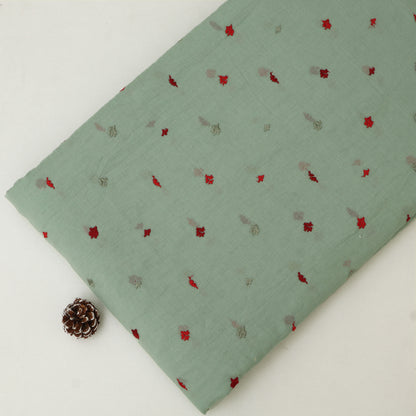 Green fabric with small red and gray patterns on a white background