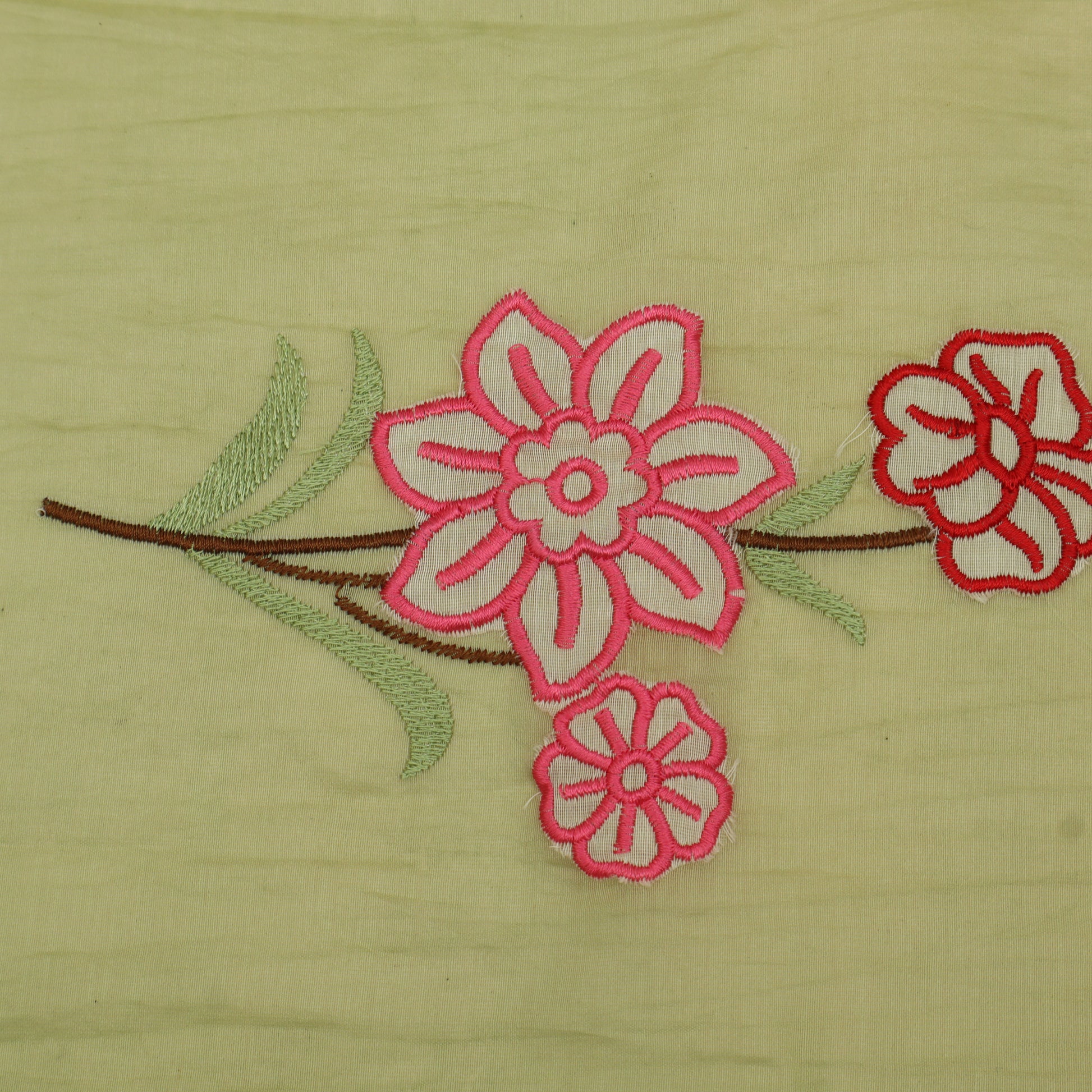 Embroidered pink flowers on a green fabric background
