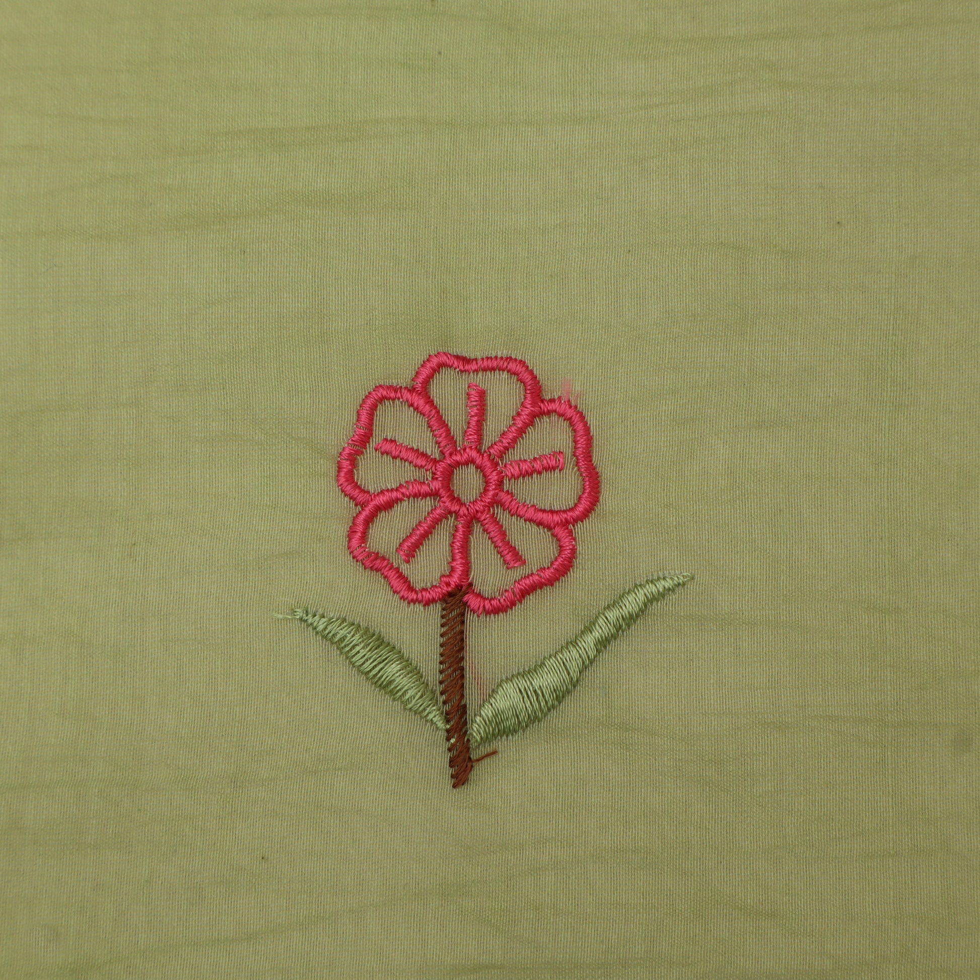 Embroidered pink flower with green leaves on a beige fabric background