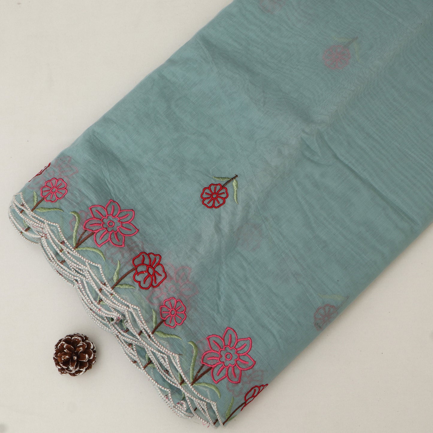 Teal fabric with red floral embroidery on a light gray background