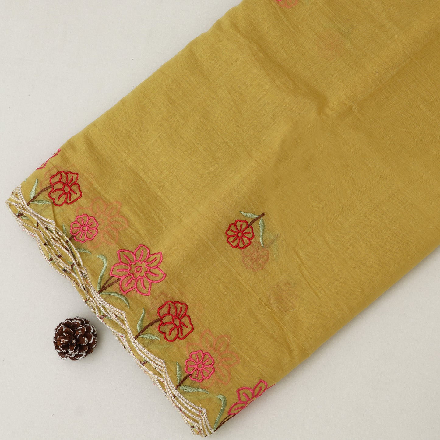 Mustard yellow fabric with red floral embroidery on a light gray background