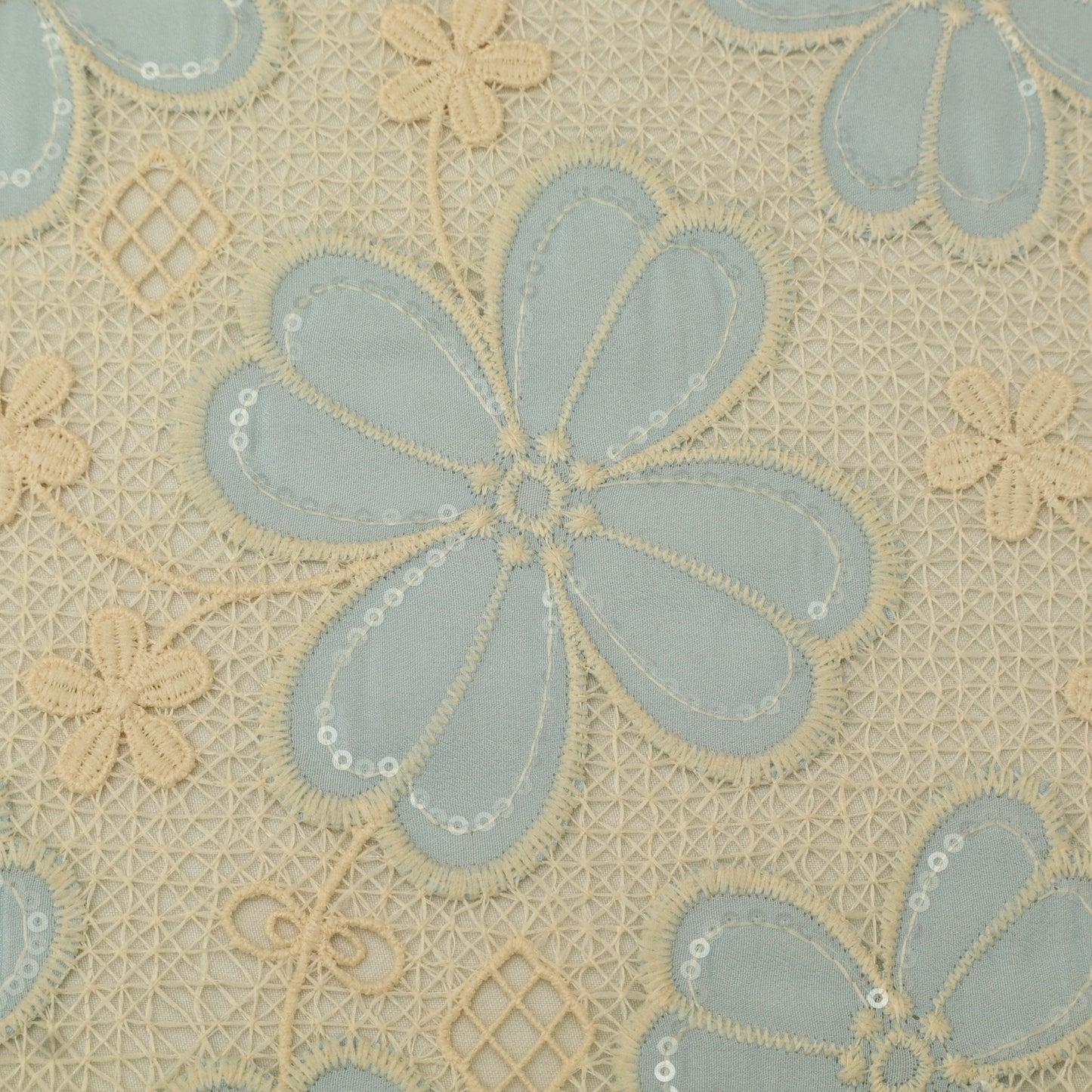 Close-up of floral embroidery pattern with blue and beige flowers on a textured fabric background.