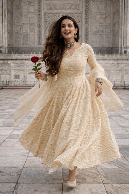 Woman in a beige dress holding a red rose in front of a marble wall.