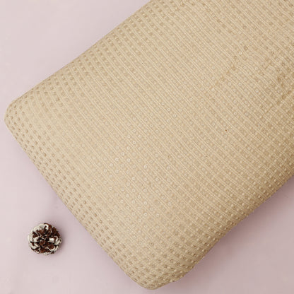 Beige textured fabric with a small decorative item on a light pink background