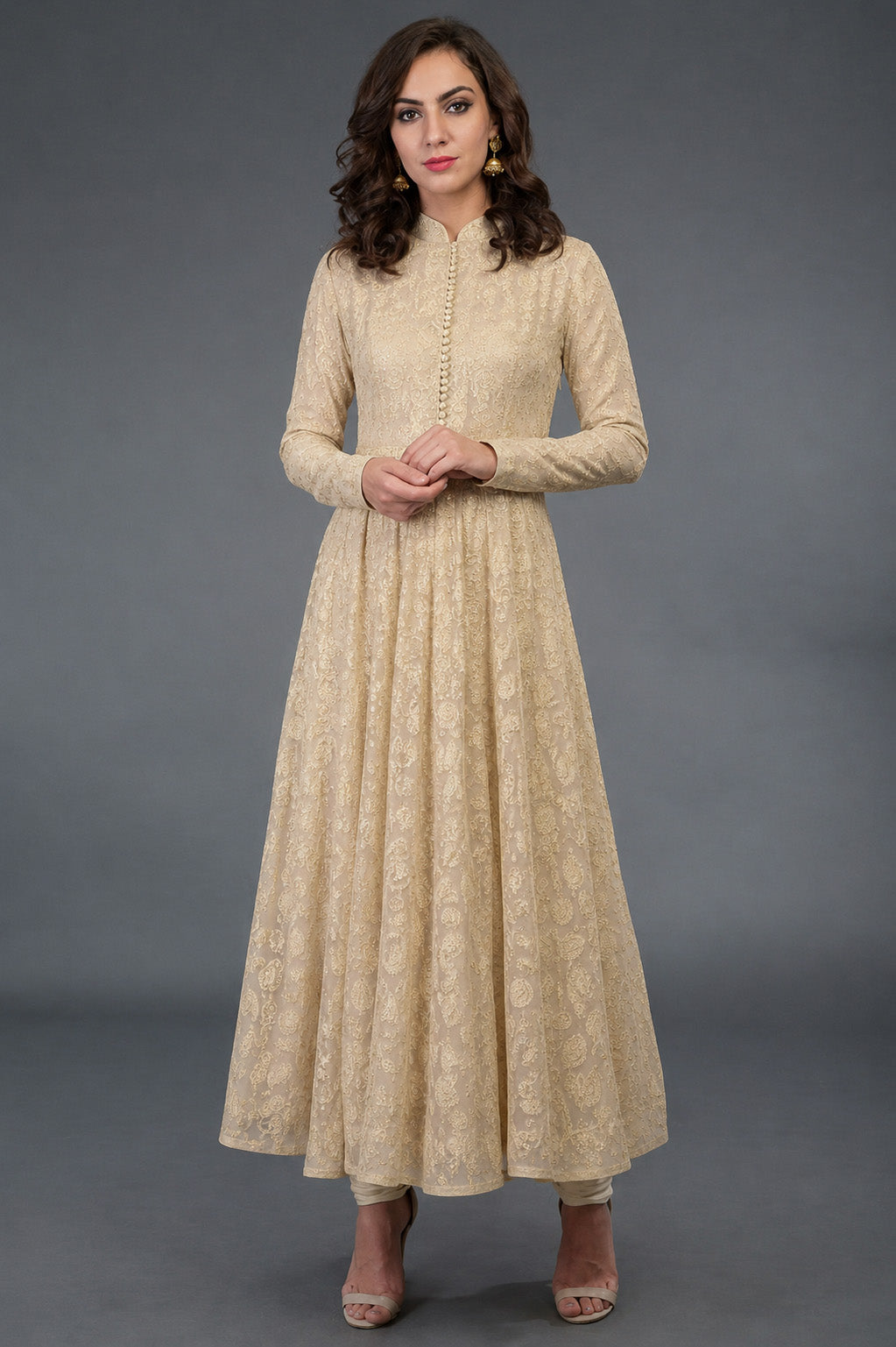 Woman wearing a beige long dress with a subtle pattern against a gray background