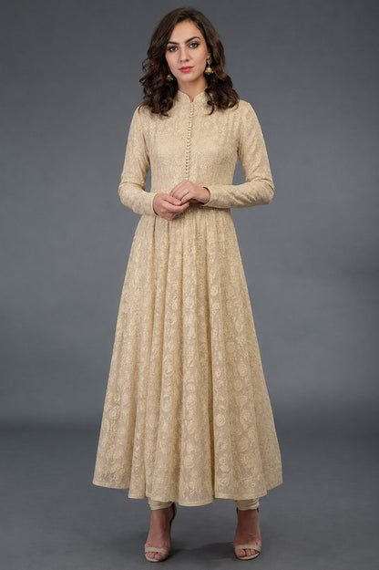 Woman wearing a beige long dress with a subtle pattern against a gray background