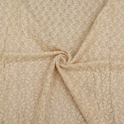 Beige fabric with a subtle pattern, possibly floral or paisley, in a close-up view.