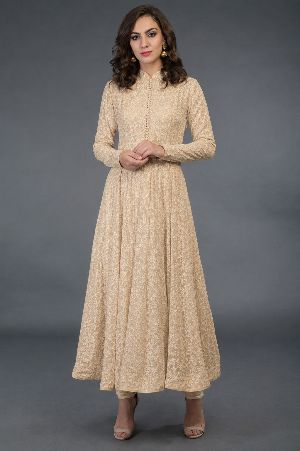Woman wearing a beige long-sleeve dress against a gray background