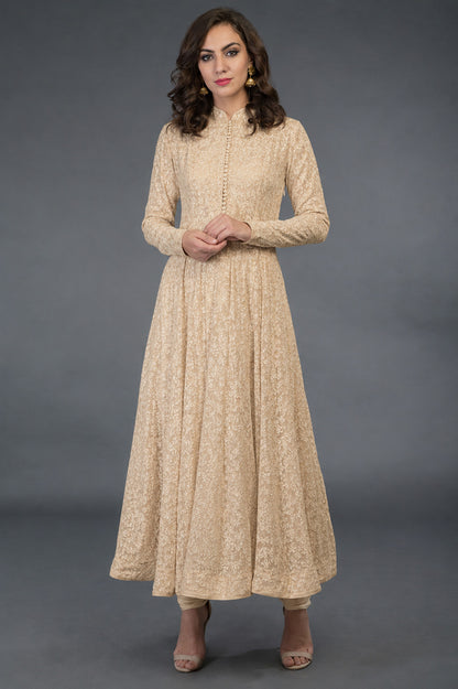 Woman wearing a beige long-sleeve dress against a gray background