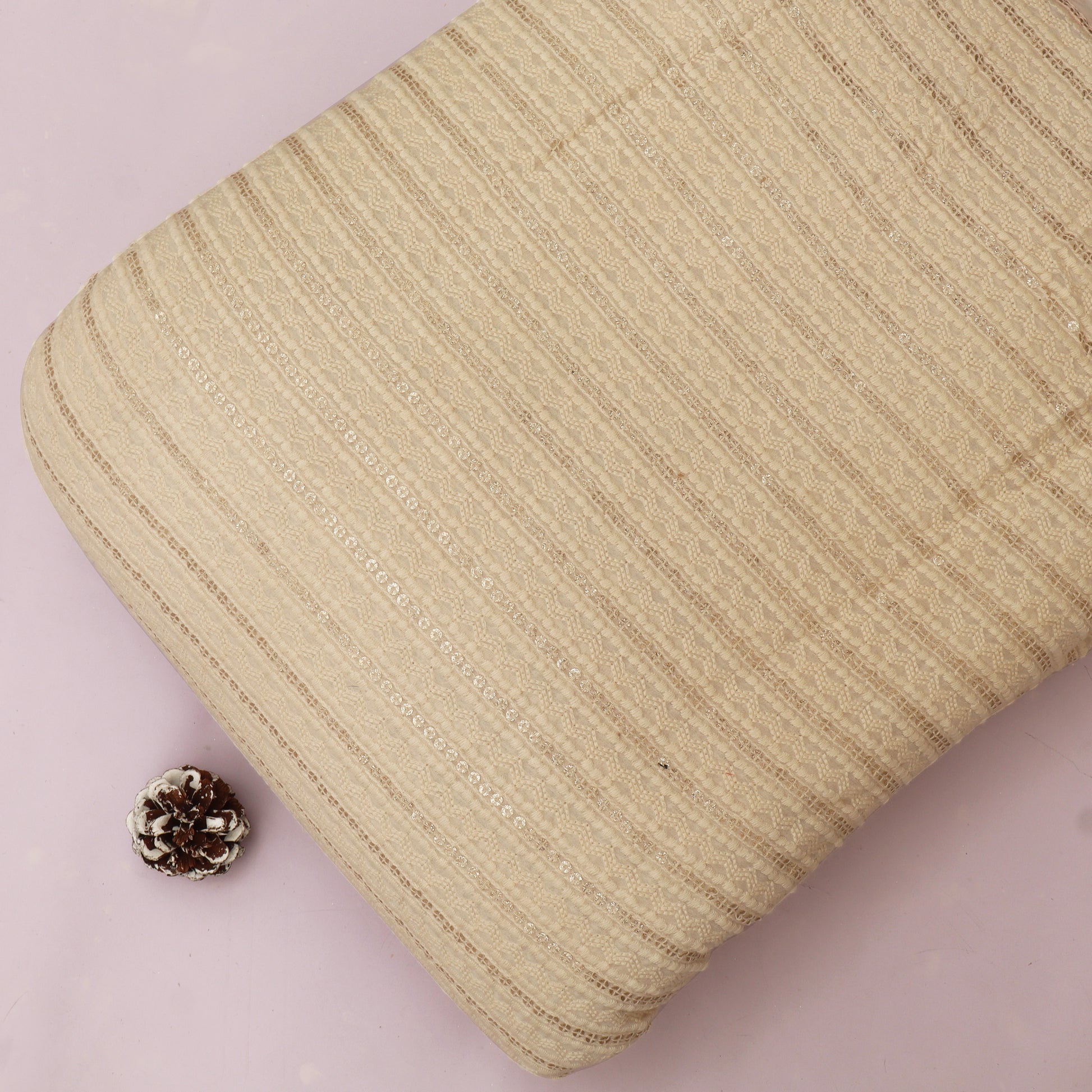 Beige textured pouch with a small pine cone on a light pink background
