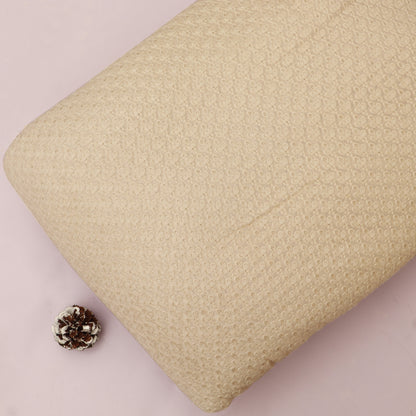 Beige textured pillow with a small pine cone on a pink background