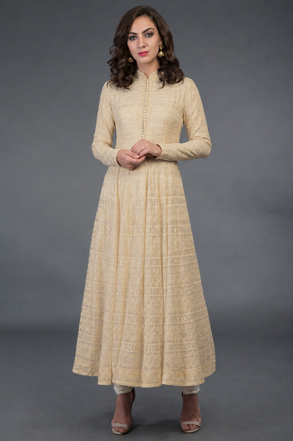 Woman wearing a beige long dress against a gray background