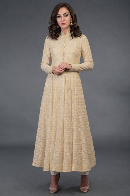 Woman wearing a beige long dress against a gray background