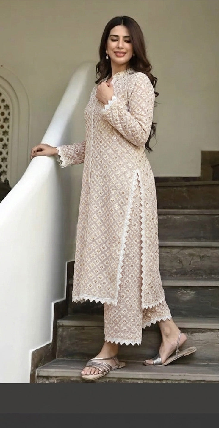 Woman in a beige lace dress standing on a staircase.