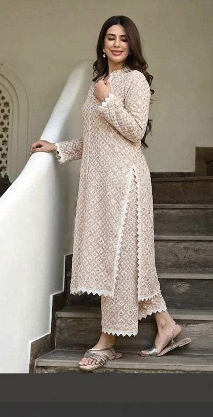 Woman in a beige lace dress standing on a staircase.