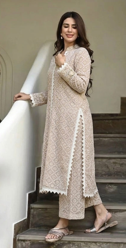 Woman in a beige embroidered outfit standing on steps indoors