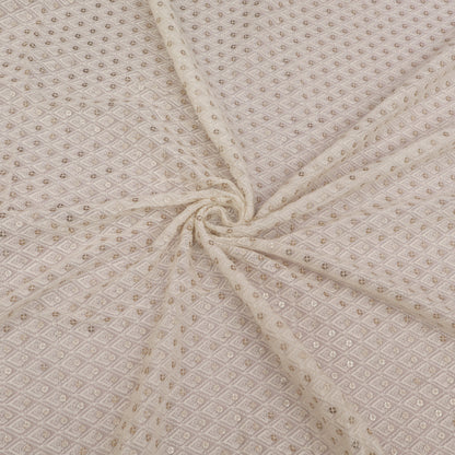 Beige fabric with a subtle pattern, folded in a way that creates a swirl.