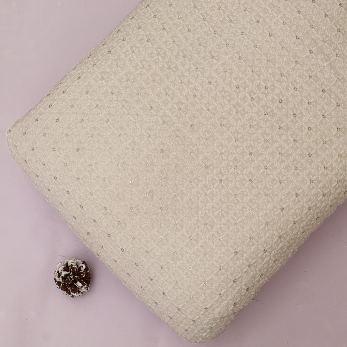 Textured White pillow on a White background with a pine cone.