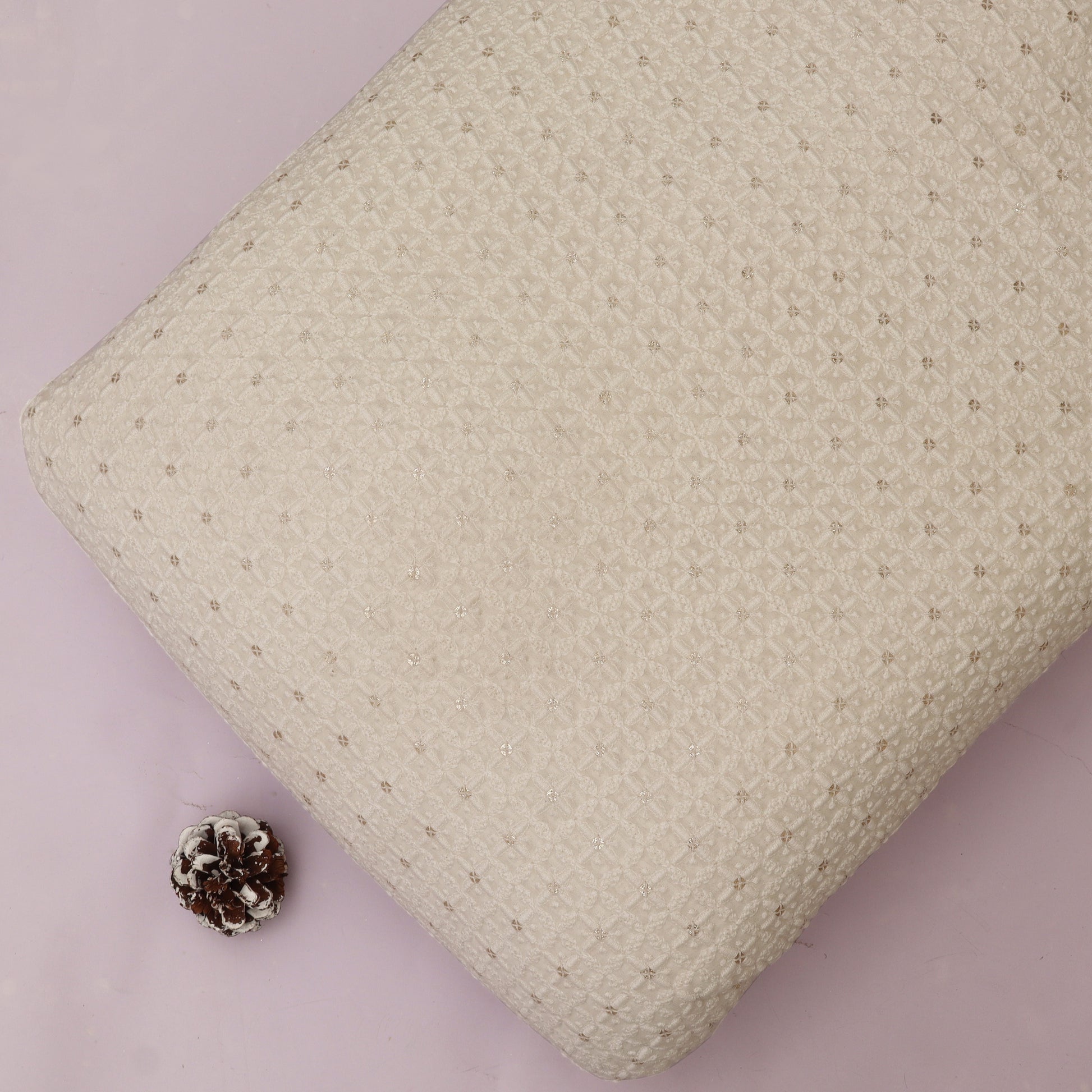 Textured White pillow on a White background with a pine cone.