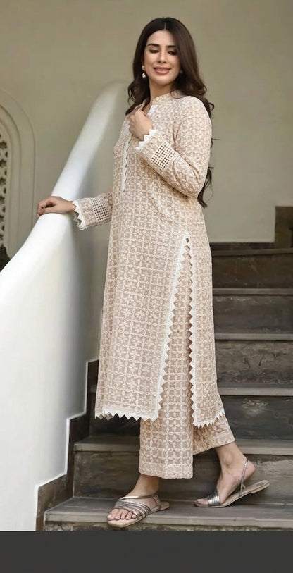 Woman in a beige embroidered outfit standing on a staircase.