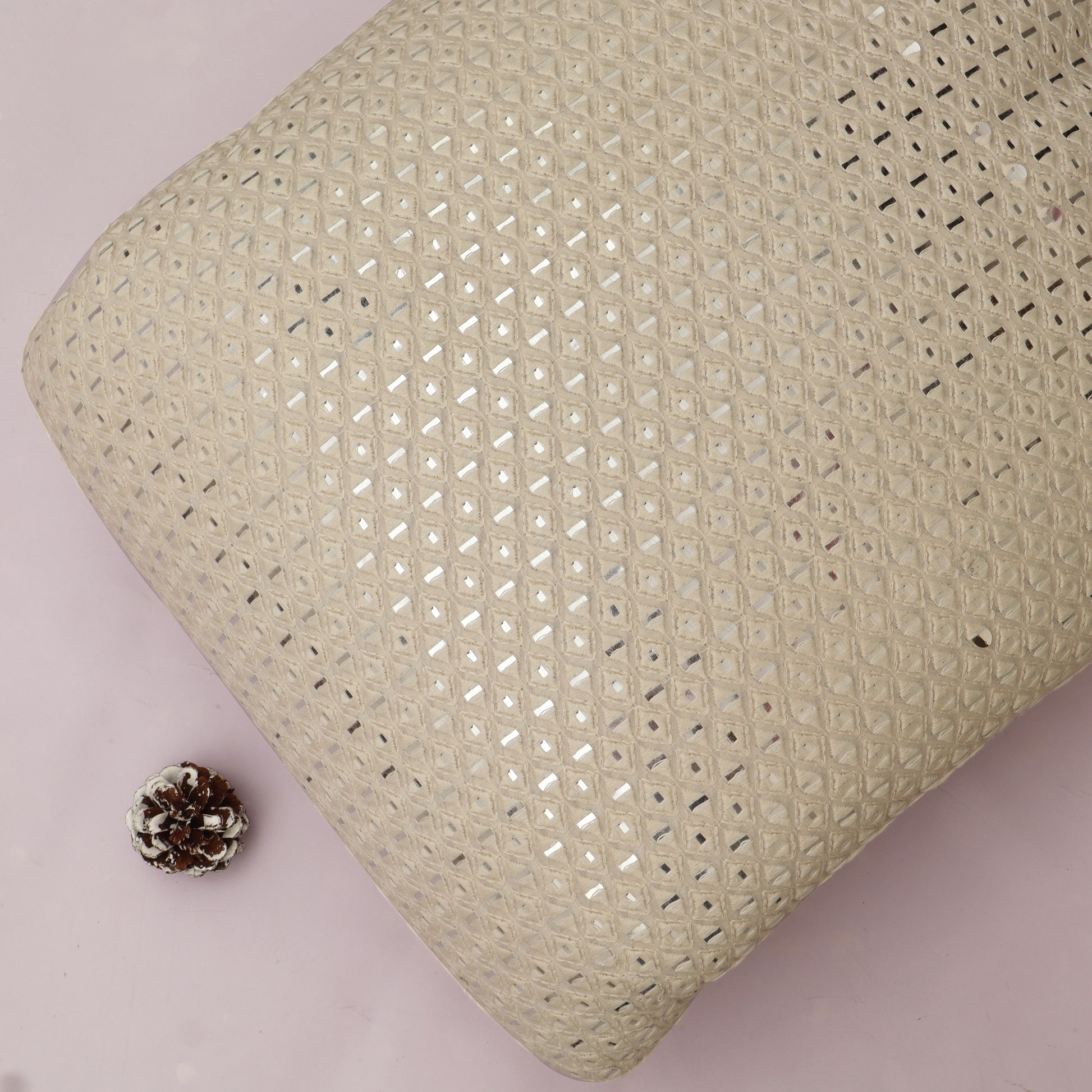 Textured White pillow with a small pine cone on a White background