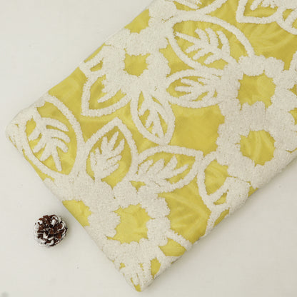 Yellow fabric with white lace pattern and a pine cone on a light background