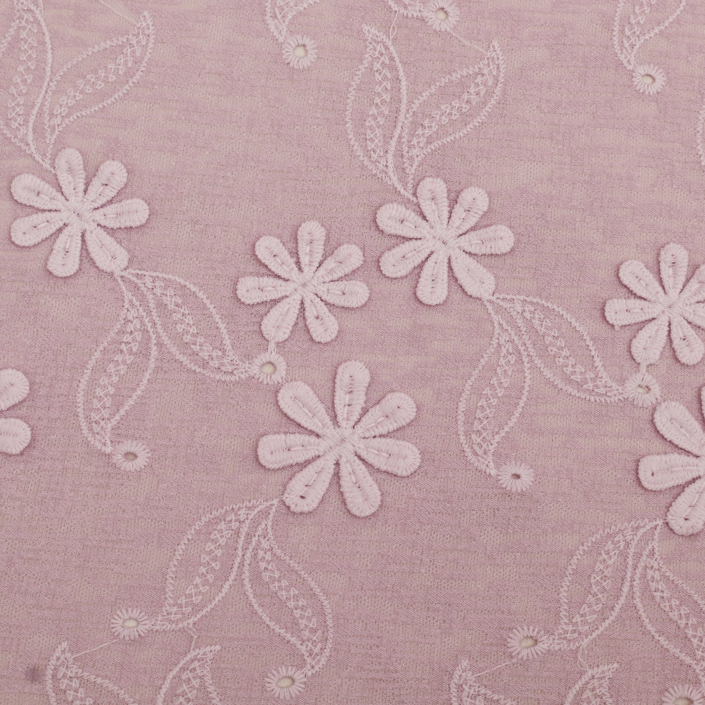 Embroidered floral pattern on a pink fabric background