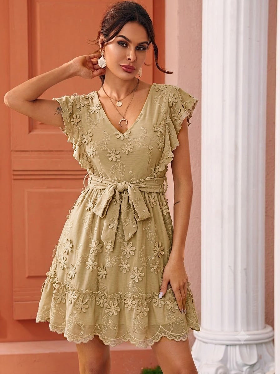 Woman wearing a beige floral dress against a pink wall.