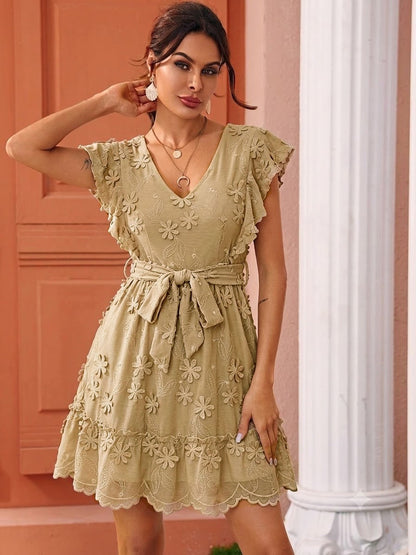 Woman wearing a beige floral dress against a pink wall.