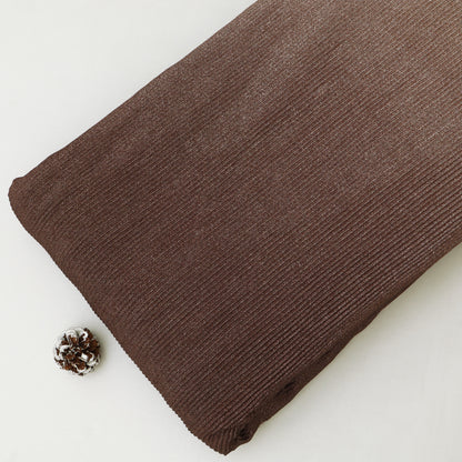 Brown fabric roll on a white background with a pine cone