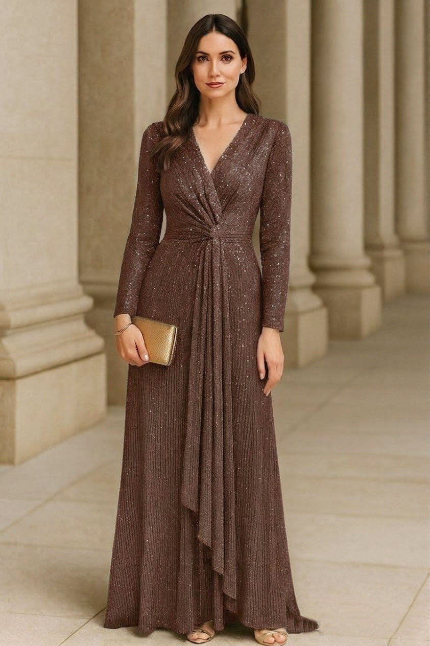 Woman in a long brown dress standing in front of classical columns.