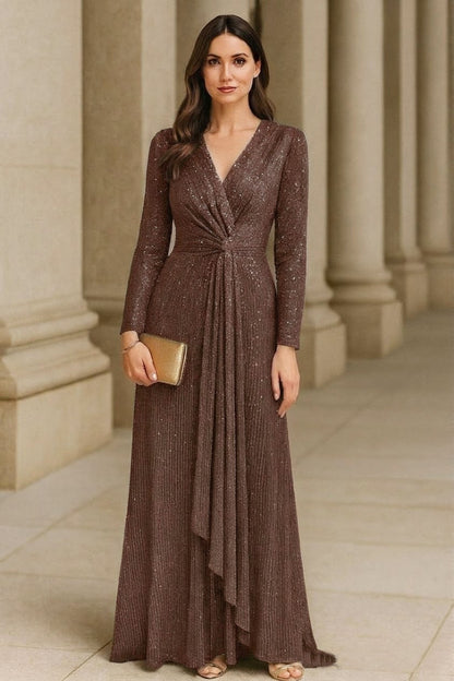 Woman in a long brown dress standing in front of classical columns.