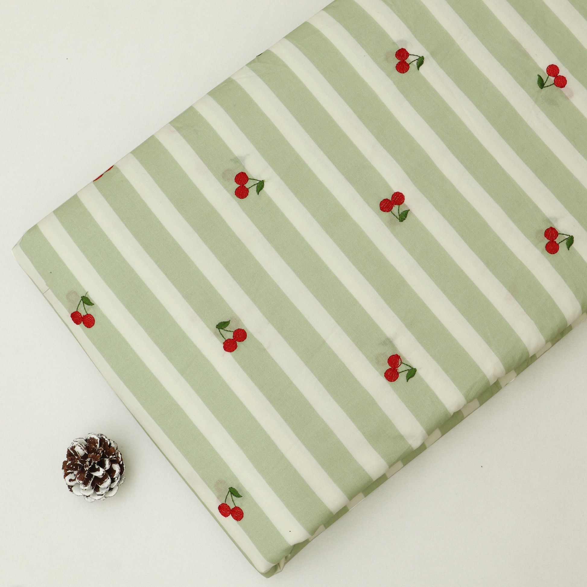 Fabric with green and white stripes and red cherries on a white background