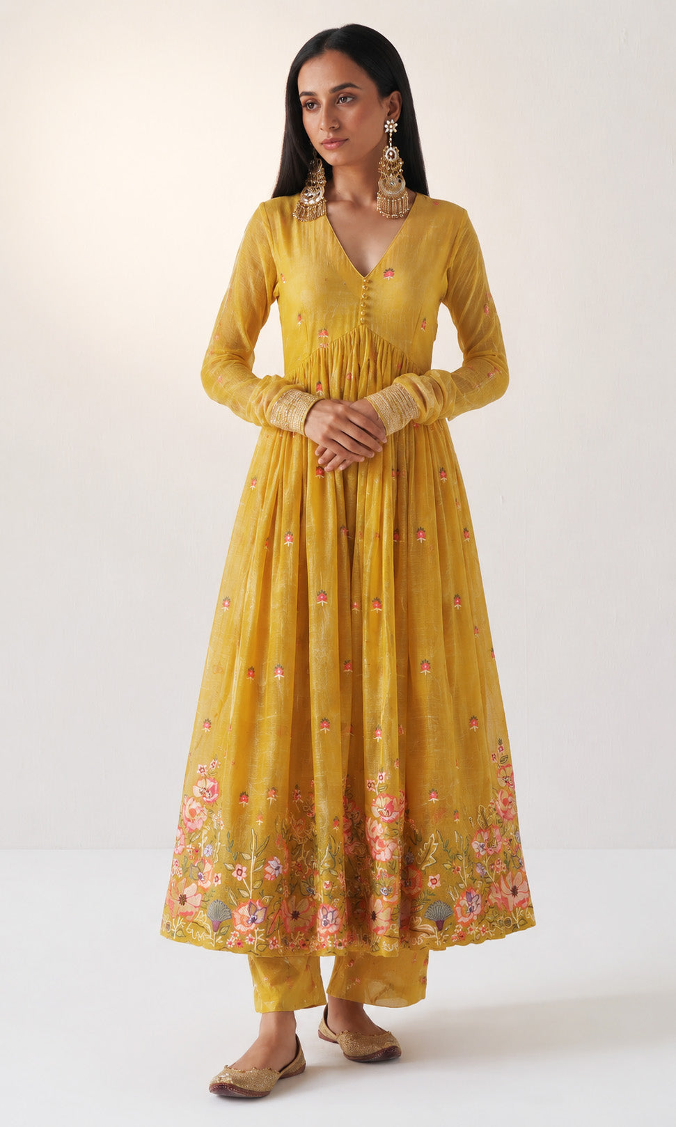Woman wearing a yellow dress with floral patterns on a white background
