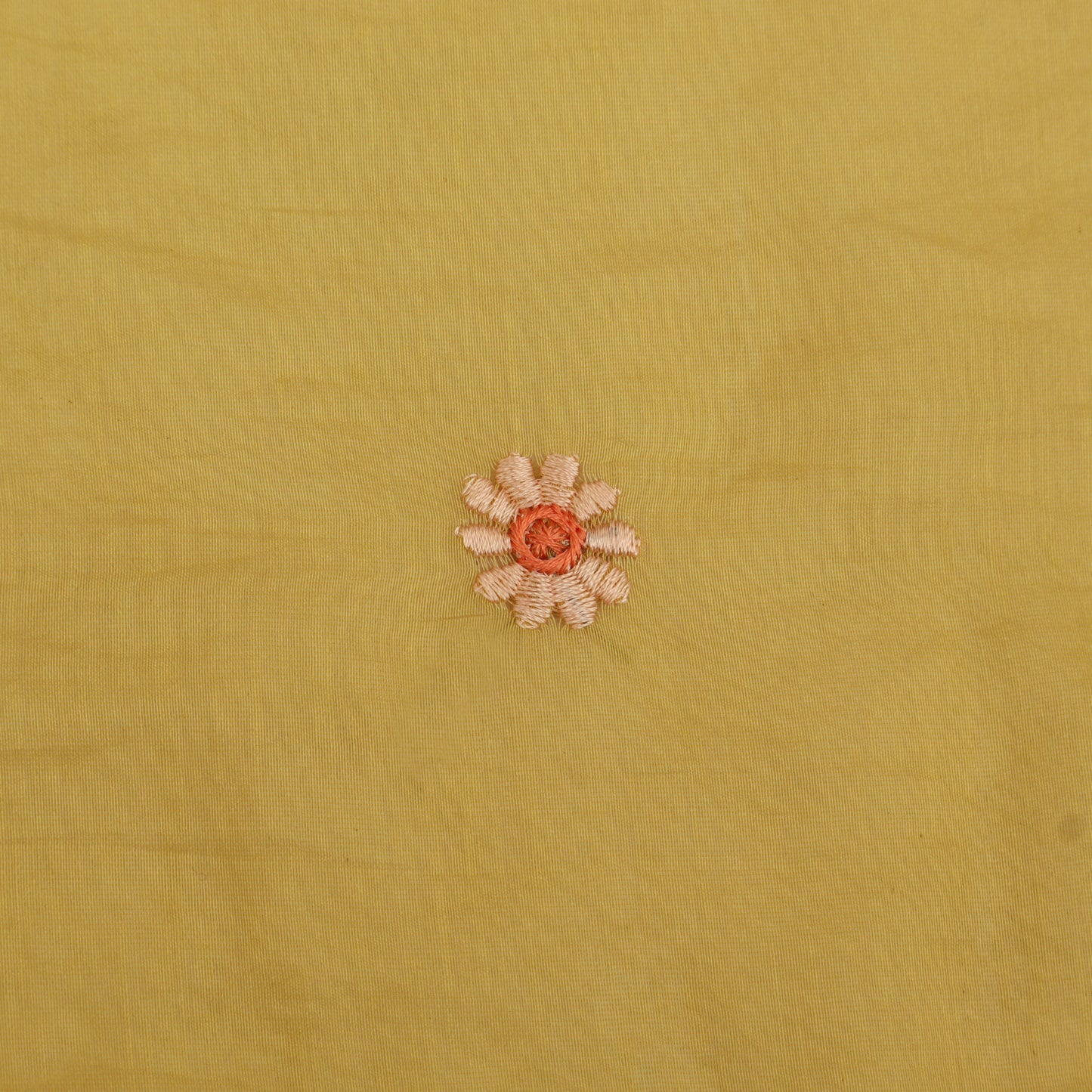 Small embroidered flower on a yellow fabric background