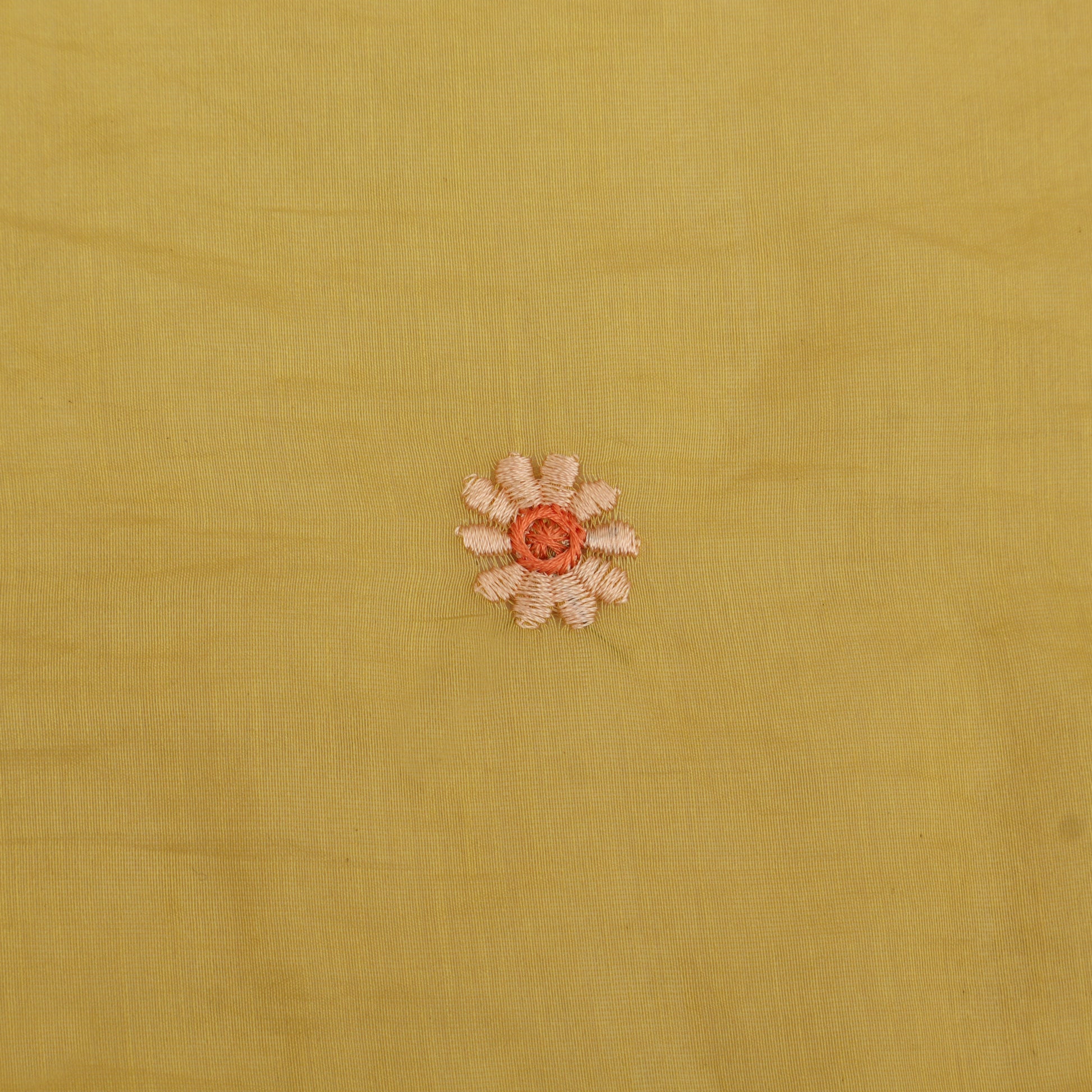 Small embroidered flower on a yellow fabric background