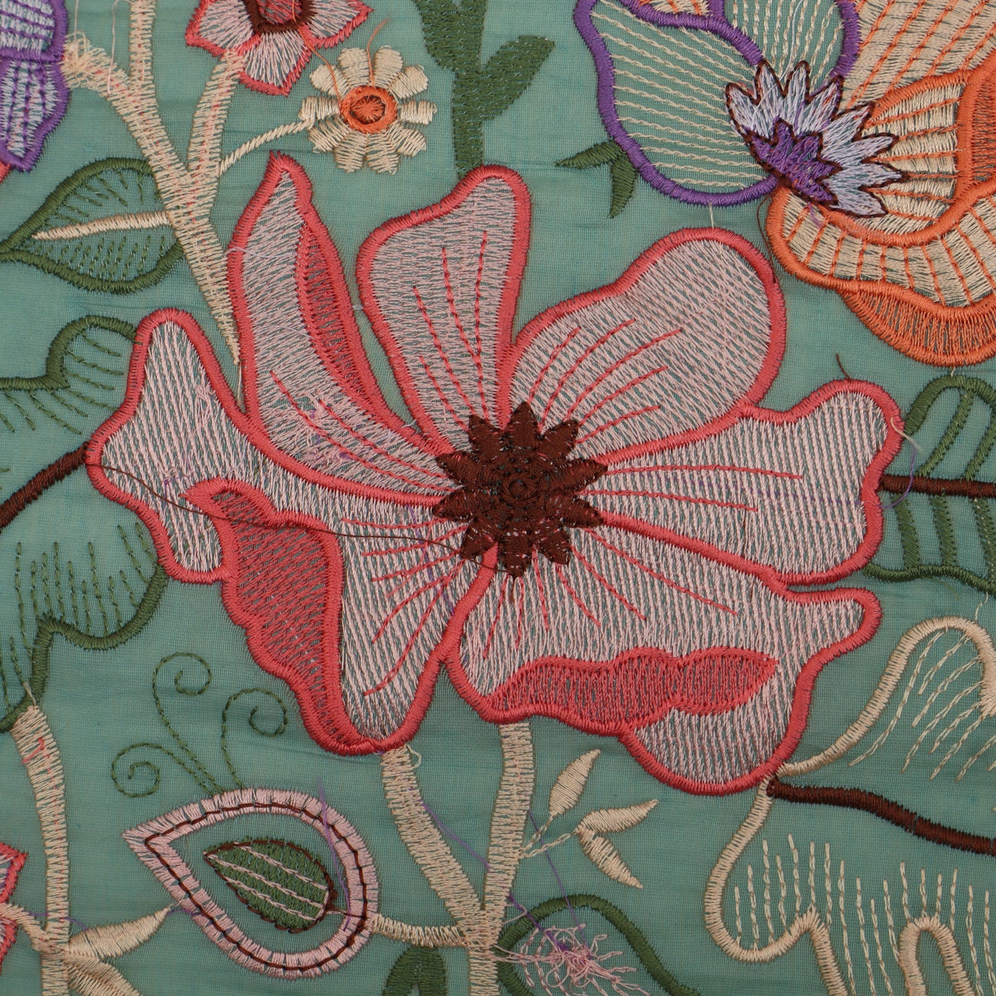 Close-up of embroidered floral design on fabric with a teal background