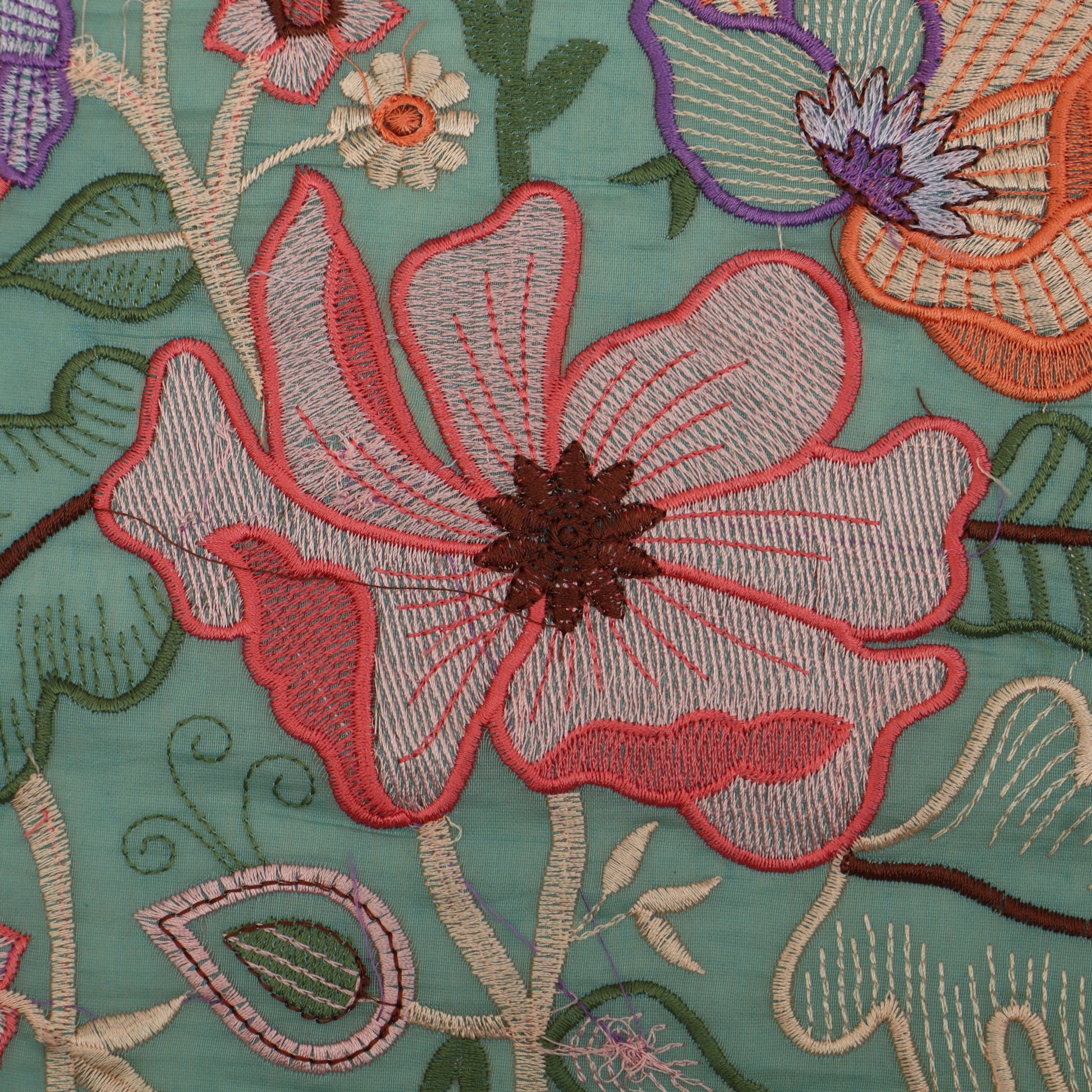 Close-up of embroidered floral design on fabric with a teal background