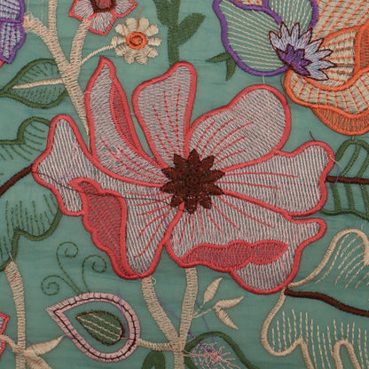 Close-up of embroidered floral design on fabric with a teal background