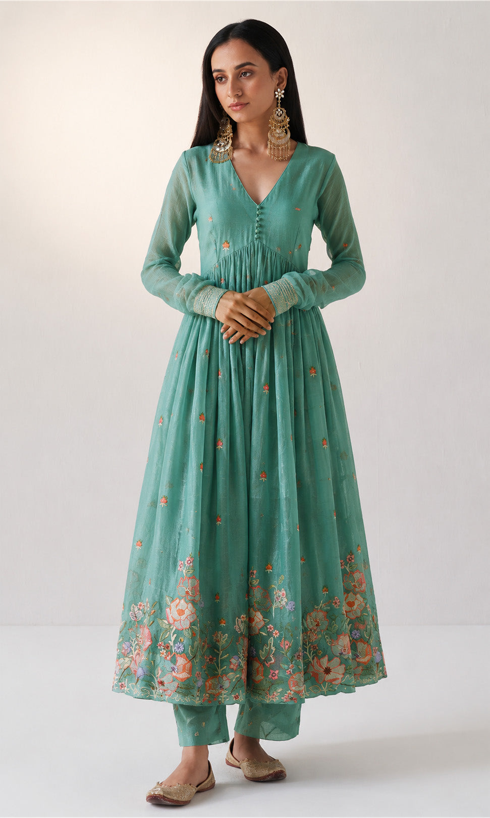 Woman wearing a teal floral dress on a white background