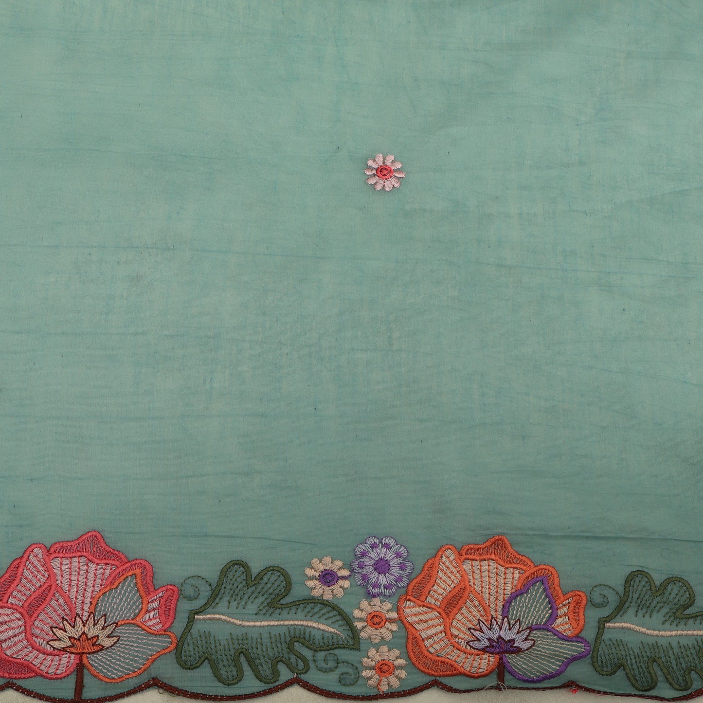 Teal fabric with floral embroidery at the bottom