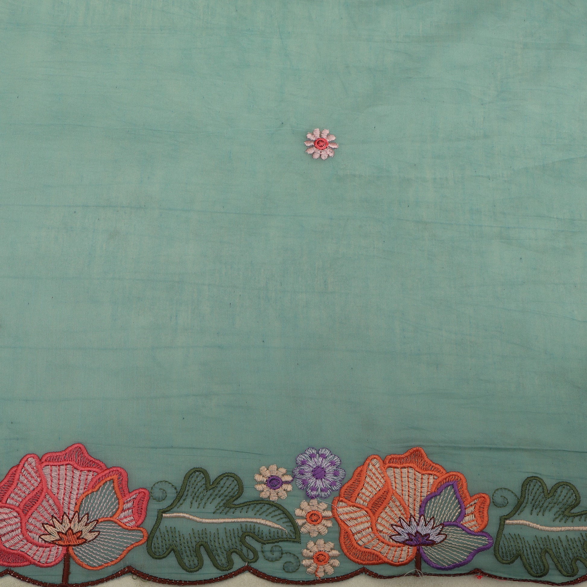 Teal fabric with floral embroidery at the bottom
