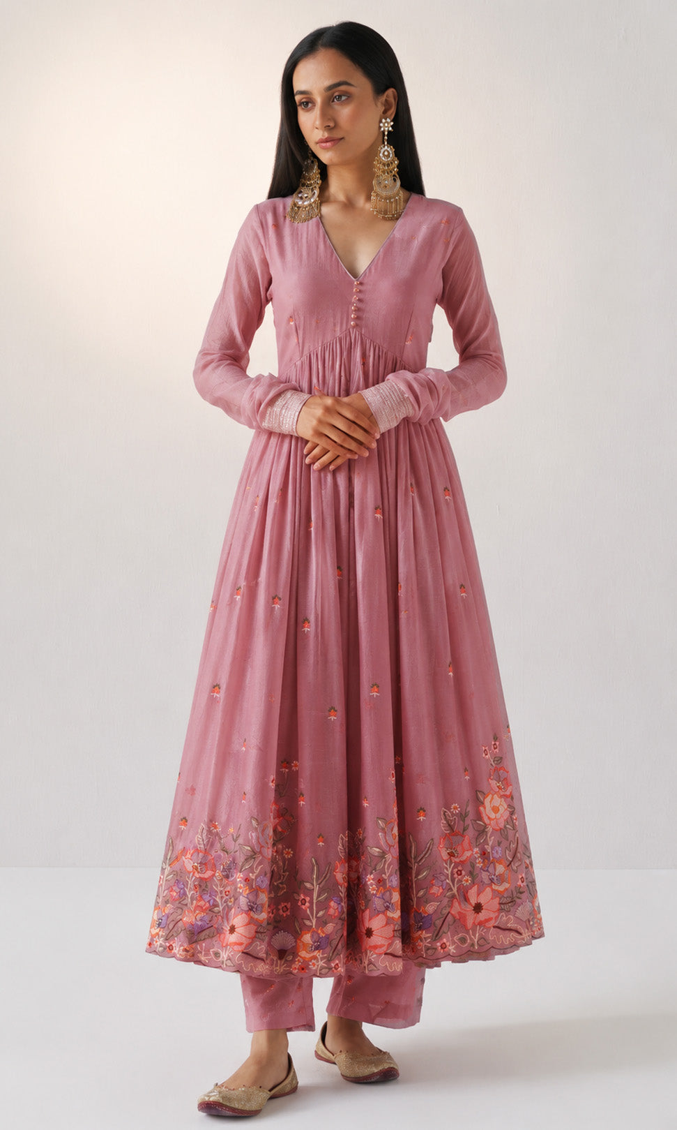 Woman wearing a pink traditional outfit with floral patterns on a white background