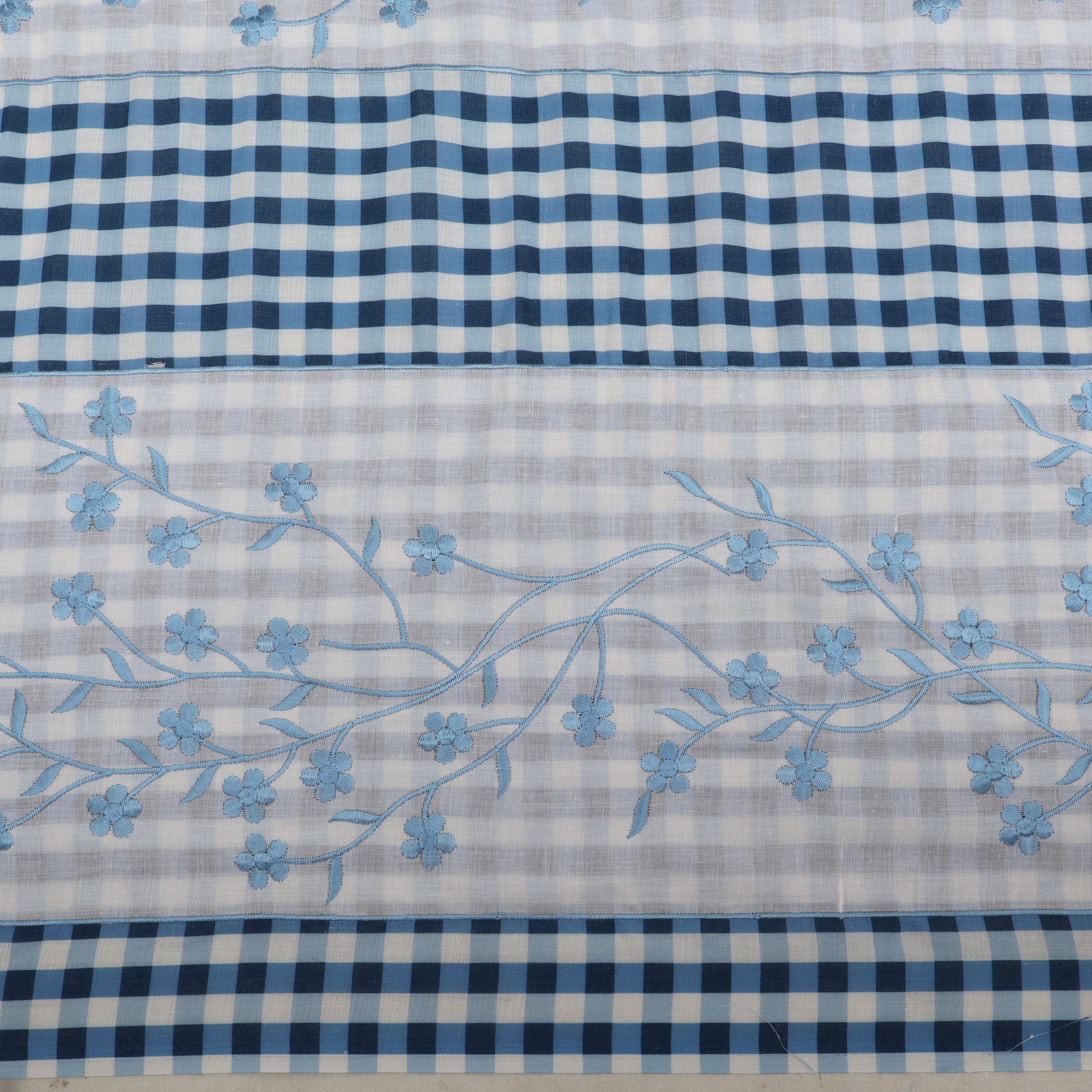 Fabric with blue floral embroidery on a checkered pattern background