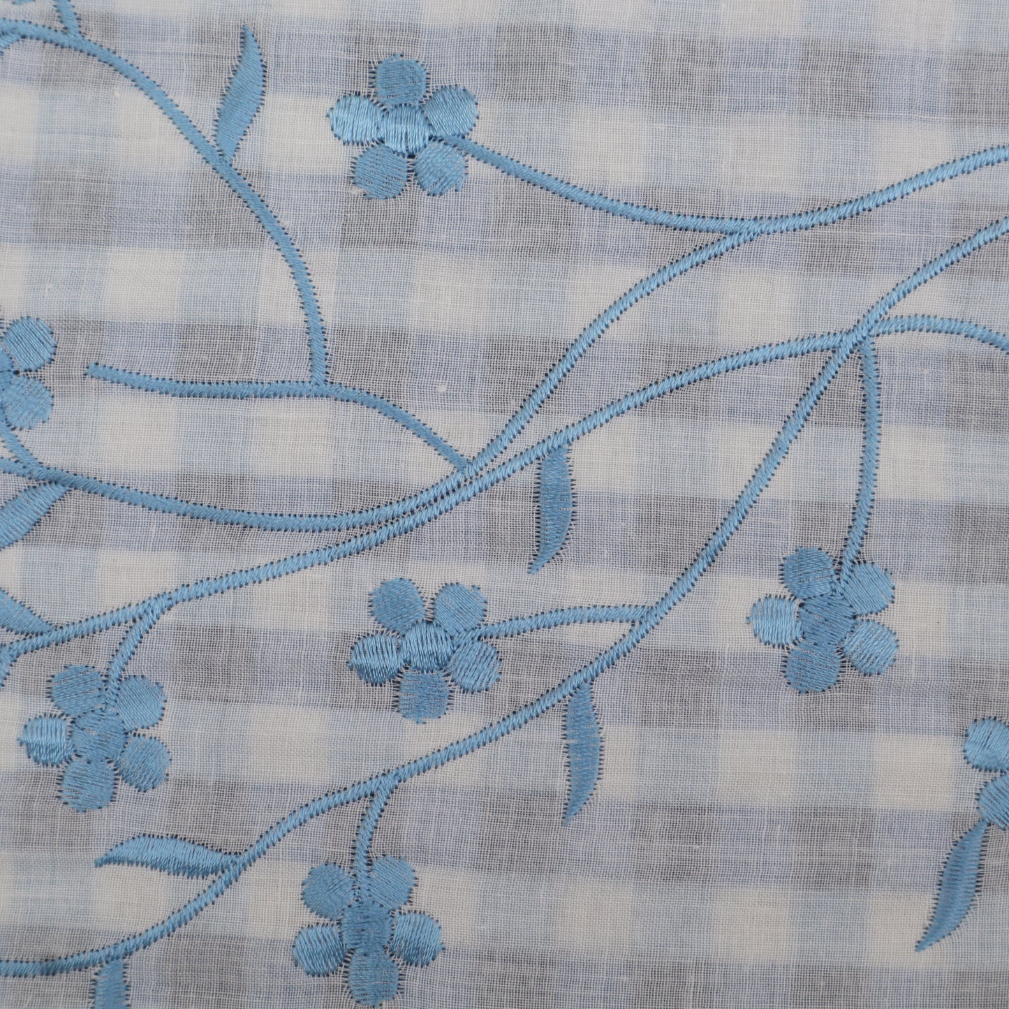 Embroidered blue floral pattern on a checkered fabric background