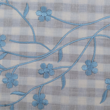 Embroidered blue floral pattern on a checkered fabric background