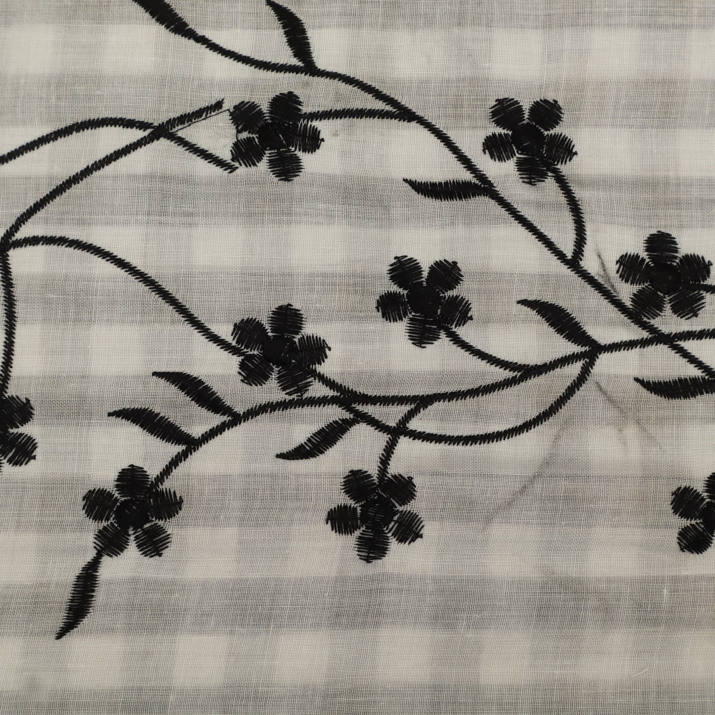 Embroidered black floral pattern on a light fabric background