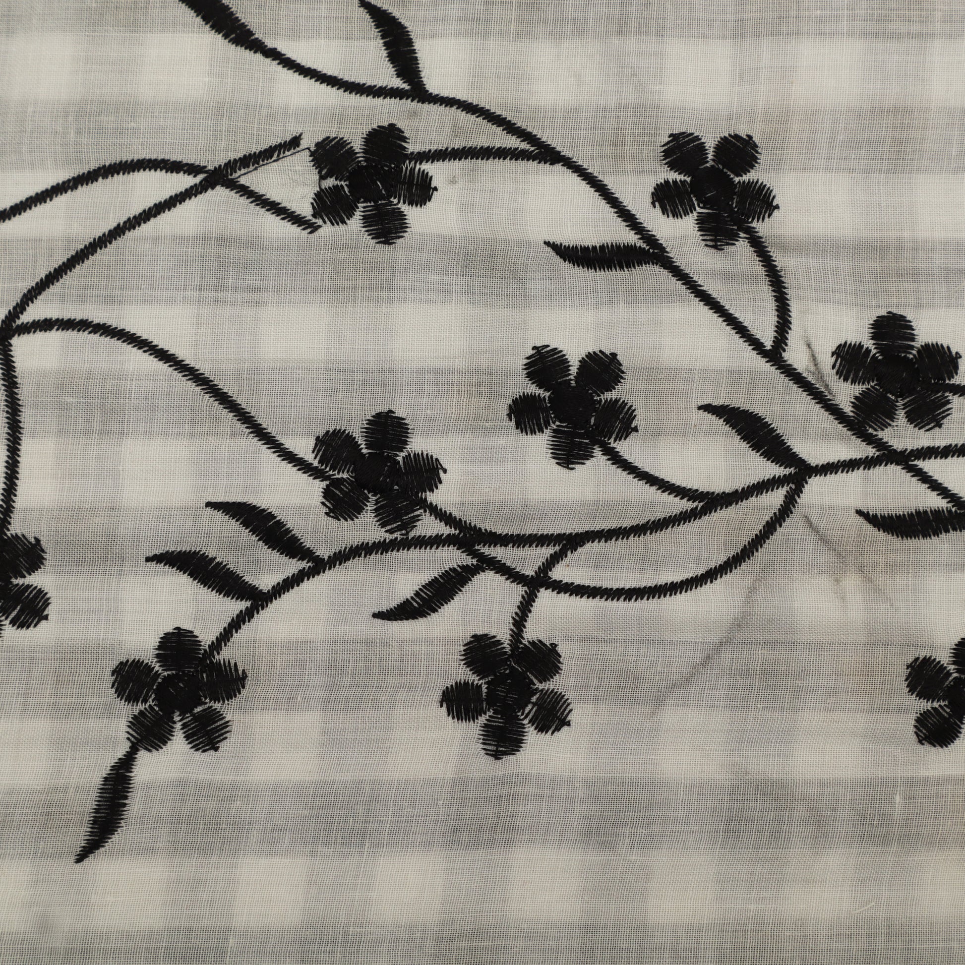 Embroidered black floral pattern on a light fabric background