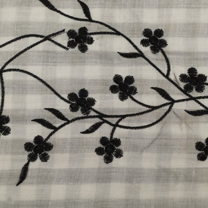 Embroidered black floral pattern on a light fabric background